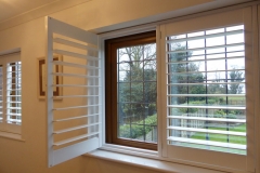 White TPost Shutters On Stained Window with Left Shutter Open