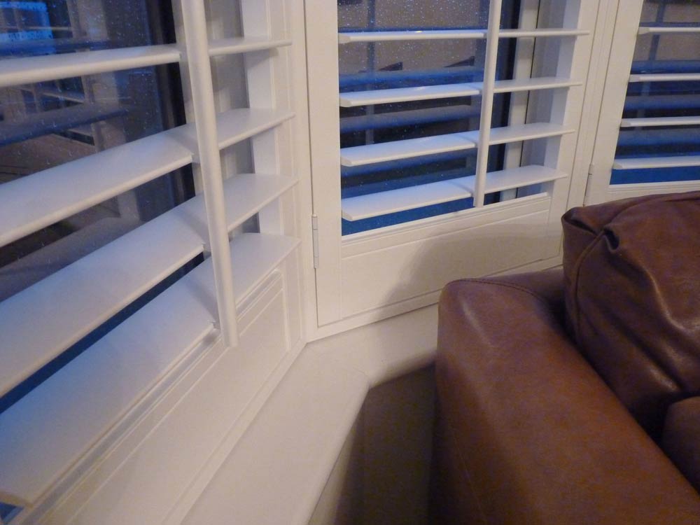 Angle vinyl shutter view around a bay window